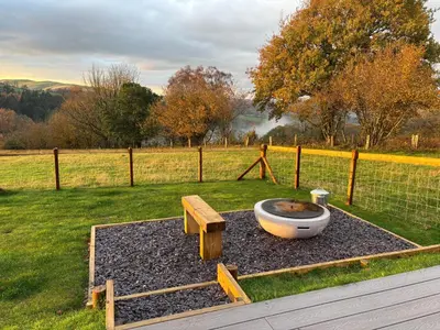 a garden with a large bowl and a bench and a fence at Four Paws Glamping in Aberystwyth