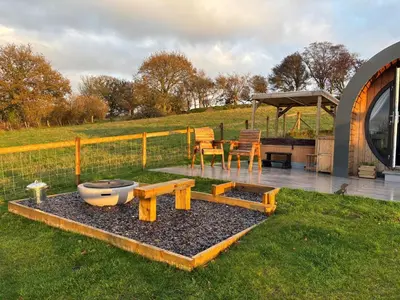 a garden with a table and chairs and a fence at Four Paws Glamping in Aberystwyth