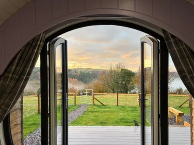 an open door with a view of a field at Four Paws Glamping in Aberystwyth