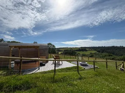 a cabin in a field with a table and a fence at Four Paws Glamping in Aberystwyth