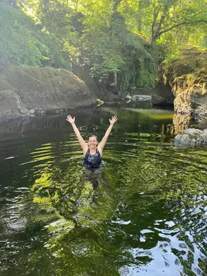 a woman swimming in a river with her arms in the water at Pont Wrysgen Cottage 'the gateway to Snowdonia' in Mallwyd