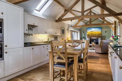 a kitchen with white cabinets and a wooden table and chairs at Long Barn in Ludlow