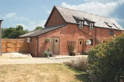 a red brick house with a wooden fence at Orchard Farm in Ludlow