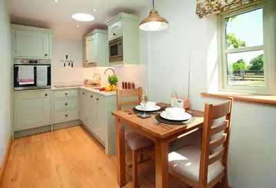 a kitchen with a wooden table and a table and chairs at Orchard Farm in Ludlow