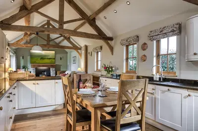 a kitchen with white cabinets and a wooden table with chairs at Orchard Farm in Ludlow