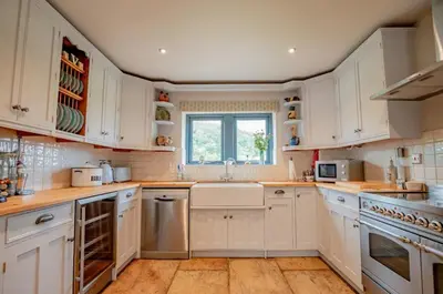 a kitchen with white cabinets and a window at 5 bedroom Barn, Ludlow in Caynham