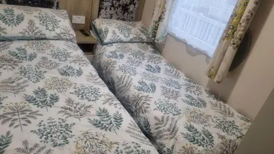 two beds in a room with a comforter at Privately owned Pet friendly caravan in Llanddwywe