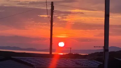 a sunset over the ocean with two telephone poles at Privately owned Pet friendly caravan in Llanddwywe