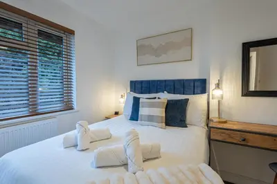 a bedroom with a large white bed with blue accents at Judith House in Shrewsbury