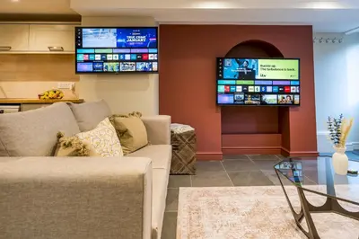 a living room with a couch and two televisions at Fantastic 6-bedroom house close to Shrewsbury town - Pass the Keys in Shrewsbury