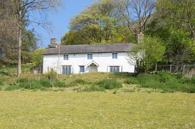 an old white house in a field with trees at Tanat Valley Farmhouse in Hirnant