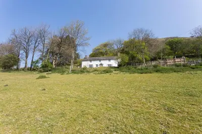 a large field with a white house in the background at Tanat Valley Farmhouse in Hirnant