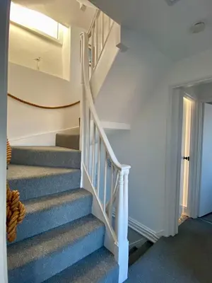 a staircase in a home with white walls and blue carpet at Harbour View in Aberaeron