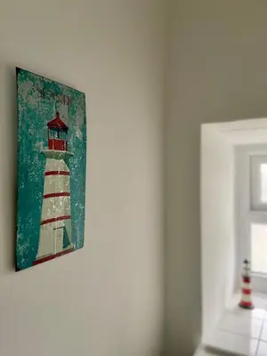 a painting of a lighthouse hanging on a wall at Harbour View in Aberaeron