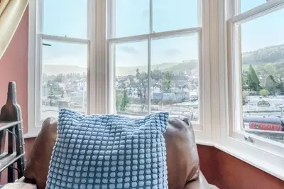 a couch with a blue pillow in front of a window at 5 Bed in Llangollen oc-l34205 in Llangollen
