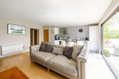 a living room with a couch and a kitchen at Luxury Lakeside Lodge with Hot Tub in Ratlinghope in Ratlinghope