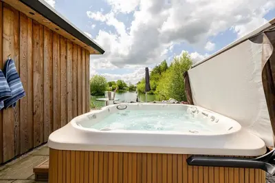 a jacuzzi tub sitting on top of a deck at Luxury Lakeside Lodge with Hot Tub in Ratlinghope in Ratlinghope