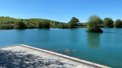 a view of a large lake with trees and hills at Luxury Lakeside Lodge with Hot Tub in Ratlinghope in Ratlinghope