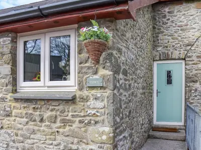 a stone cottage with a window and a basket of flowers at Towy Cottage - Uk49589 in Llansawel