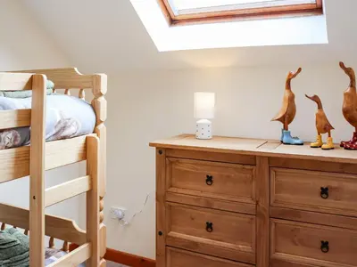 a bedroom with a bunk bed and a wooden dresser at Towy Cottage - Uk49589 in Llansawel