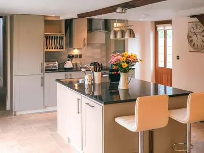 a kitchen with white cabinets and a black counter top at Lower House Barn in Staunton on Wye
