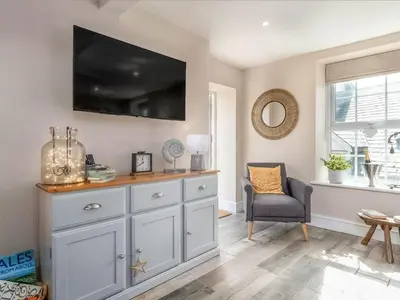 a living room with a dresser with a television on the wall at Seagrass Cottage in Aberdyfi