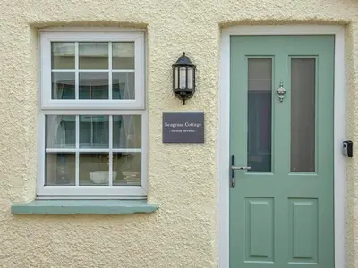a green door and a window on a building at Seagrass Cottage in Aberdyfi