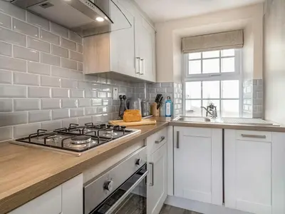 a white kitchen with a stove and a sink at Seagrass Cottage in Aberdyfi