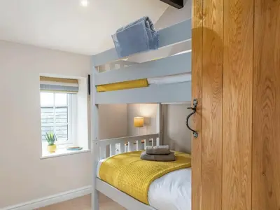 a bedroom with a bunk bed with a yellow blanket at Seagrass Cottage in Aberdyfi