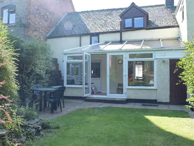 an extension to a house with a patio and a table at Canon's Cottage in Clun
