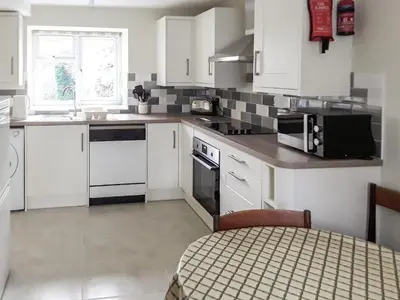 a kitchen with white cabinets and a black microwave at Canon's Cottage in Clun