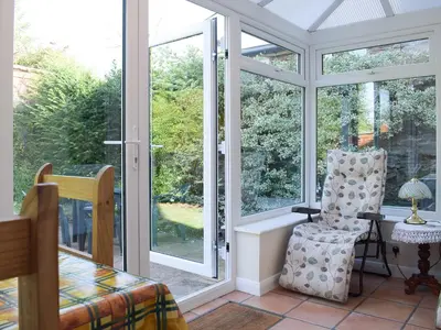 a screened in porch with a chair and a window at Canon's Cottage in Clun