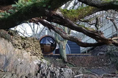 a building with a round window on a stone wall at Salt Marsh Cabin - Hot tub-Sauna in Barmouth