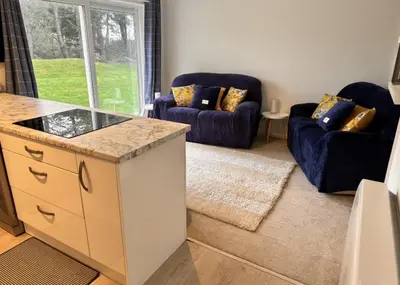 a living room with two blue couches and a kitchen at Pet friendly 3 bed retreat for beach, castle, golf in Harlech