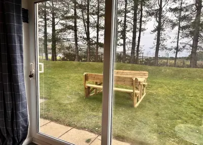 a sliding glass door with a bench in the yard at Pet friendly 3 bed retreat for beach, castle, golf in Harlech
