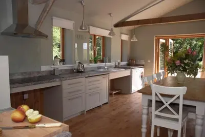 a large kitchen with white cabinets and a table at Alder Barn in Clun