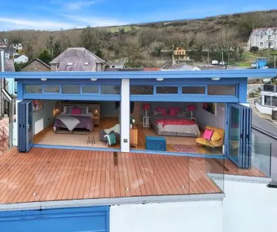 a house with a deck with a bedroom and a bed at Y Llofft in New Quay