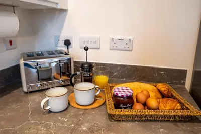 a kitchen counter with a basket of bread and coffee cups at Cosy & Contemporary 2 Bed Home, Quiet Area Parking - Pass the Keys in Shrewsbury