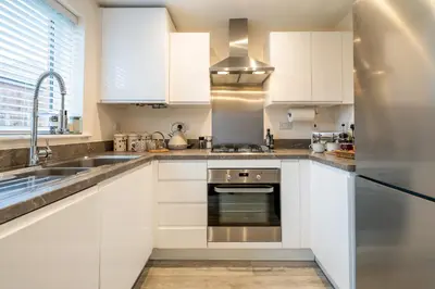 a kitchen with white cabinets and a stainless steel oven at Cosy & Contemporary 2 Bed Home, Quiet Area Parking - Pass the Keys in Shrewsbury