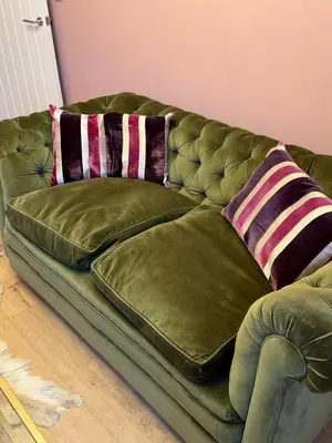 a green couch with two pillows on it at Unique Vicarage Town Cottage in Leominster