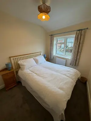 a bedroom with a large white bed and a window at Unique Vicarage Town Cottage in Leominster