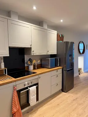 a kitchen with white cabinets and a stainless steel refrigerator at Unique Vicarage Town Cottage in Leominster
