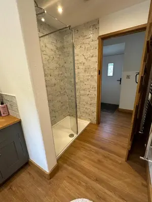a glass shower in a room with a wooden floor at Y Sgubor Bryn Banon in Bala