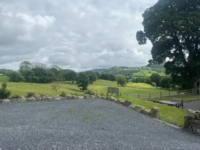a gravel road with a bench and a field at Y Sgubor Bryn Banon in Bala