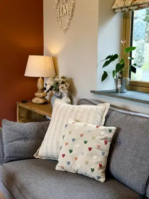 a living room with a gray couch with a pillow at Y Beudy Bach in Llanfor