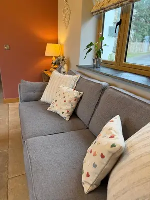 a gray couch with pillows in a living room at Y Beudy Bach in Llanfor