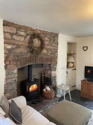 a living room with a stone fireplace and a couch at Cosy River Cottage in Brecon with a Fireplace in Merthyr Cynog