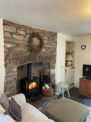a living room with a stone fireplace with a stove at Cosy River Cottage in Brecon with a Fireplace in Merthyr Cynog