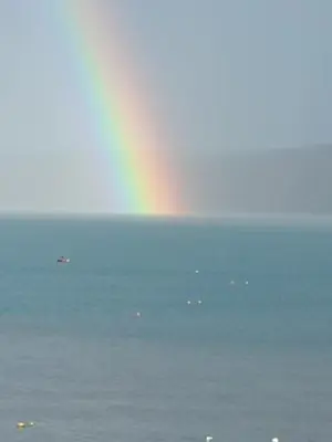 a rainbow over a body of water with boats at Canad Adar - Song of the Birds - Teifi Valley in Llanwenog