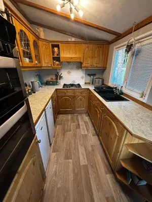a kitchen with wooden cabinets and wooden floors at The Little lodge on the lake in Welshpool